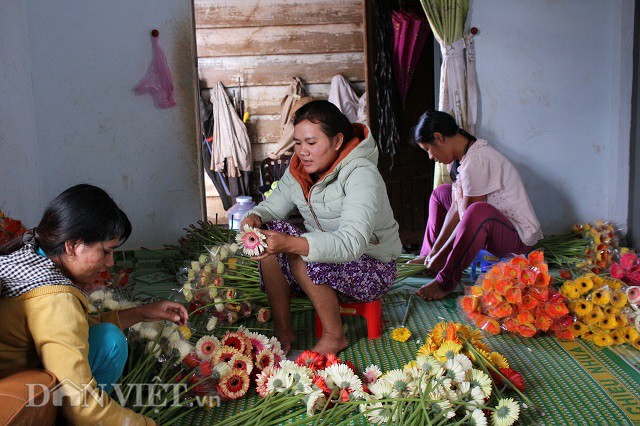 Vợ anh Điền (người ngồi sát cửa) và hai cháu của anh Điền đang lồng những cành hoa vào bịch 10 để chuẩn bị cho thương lái mang đi TP. Hồ Chí Minh.